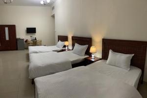 a hotel room with three beds with white sheets at Family rooms with beach view يستضيف مكان الإقامة هذا العائلات فقط in Ajman 