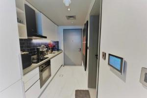 a kitchen with white counters and a hallway with a door at Modern Apartment close to Burj Khalifa in Al Faq‘