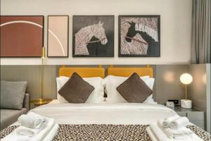 a bedroom with a large bed with four pictures on the wall at Modern Apartment close to Burj Khalifa in Al Faq‘