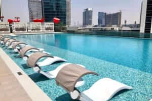 a swimming pool with chaise lounge chairs on a building at Modern Apartment close to Burj Khalifa in Al Faq‘