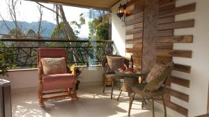einen Balkon mit Stühlen, einem Tisch und einem Fenster in der Unterkunft Los Ocobos Libano Tolima - Suite, Hostal y Restaurante in Líbano