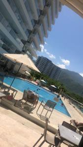 uma piscina com espreguiçadeiras e um edifício em Exclusivo Sector 1 Cuadra Playa em Santa Marta