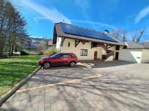 een rode auto geparkeerd op een parkeerplaats voor een huis bij Župnijski apartmaji in Dolenjske Toplice