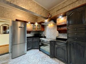 een keuken met houten kasten en een roestvrijstalen koelkast bij Delightful 3BR home in Zamalek (no visits) in Caïro