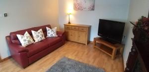 a living room with a red couch and a flat screen tv at Laurelbrook Town House in Magherafelt
