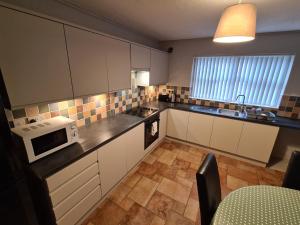 a small kitchen with white cabinets and a microwave at Laurelbrook Town House in Magherafelt +15 photos