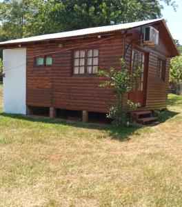 a small wooden cabin with a white door at Cabañas Aliwen in Puerto Bossetti