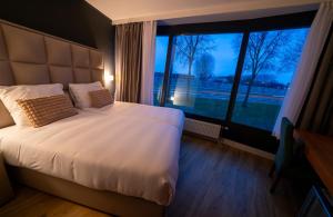 een slaapkamer met een groot bed en een groot raam bij MA Airport Hotel in Hoofddorp