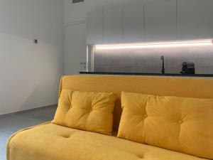 - un canapé jaune avec deux oreillers dans l'établissement Green Home - Bellagio Apt, à Côme
