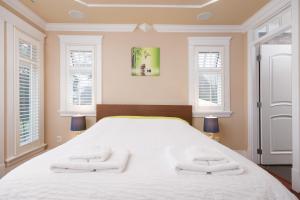 Luxurious 8-Bedroom Villa in Central Vancouver في فانكوفر: غرفة نوم بسرير ابيض كبير مع منشفتين