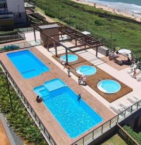 an overhead view of three swimming pools next to the beach at Resort Apto Frente Mar in Barra Velha