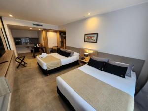 a hotel room with two beds and a kitchen at Amerian Rio Cuarto Apart & Suites in Río Cuarto