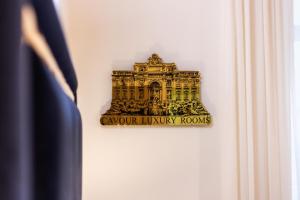 une pancarte sur un mur indiquant des chambres de luxe sculptées dans l'établissement Cavour Luxury Rooms, à Rome