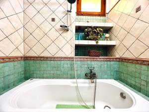 La salle de bains est pourvue d'une baignoire et de carrelage vert. dans l'établissement Nonna Sasà, à Torretta