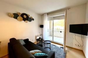 a living room with a couch and a flat screen tv at Les Naïades F27 - 1 bedroom for 4 people ! in Avène +3 photos