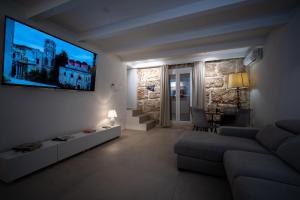 a living room with a couch and a tv on the wall at SantaTeresa19 Suite & Spa in Palermo