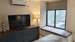 sala de estar con TV de pantalla plana y ventana en BAGUSROOM CHADSTONEPOLLUX, en Kedungg