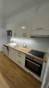 a kitchen with white cabinets and a stove top oven at Elena Villa in Hévíz