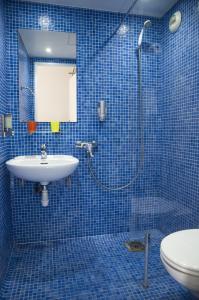 uma casa de banho em azulejos azuis com um chuveiro e um lavatório. em Solar Hotel em Paris