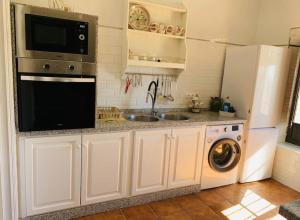 a kitchen with a sink and a stove and a microwave at Los Alcores , disfruta de la naturaleza ! in Villalba del Alcor