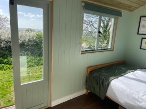 a bedroom with a bed and a window at Cosy Shepherd Huts near Newborough Forest Anglesey in Gaerwen