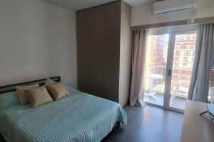 ein Schlafzimmer mit einem Bett und einem großen Fenster in der Unterkunft Oportunidad Unica Reciclado a Nuevo en Recoleta in Buenos Aires
