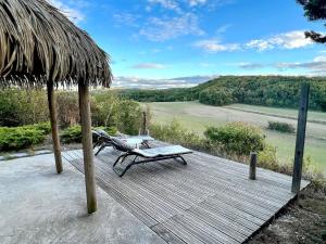 una terraza de madera con mesa de picnic y sombrilla de paja en Maison d'une chambre avec piscine partagee terrasse et wifi a Lignairolles en Lignairolles