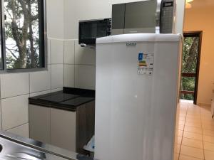 La cocina está equipada con nevera blanca y microondas. en Cabana com Vista para a Lagoa da Conceição RM9376, en Florianópolis