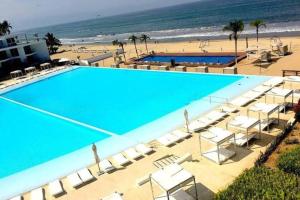 una grande piscina con sedie e una spiaggia di Paraíso marino a Nuevo Vallarta