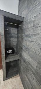 a bathroom with a stone wall with a shelf and a radio at Hotel posada MARCAS in Canc&uacute;n