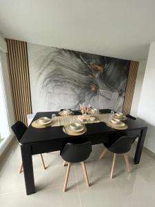 a dining room with a black table and chairs at BY NEPTUNE - Appartement Disneyland Paris in Chessy