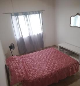 a bedroom with a bed with a red comforter and a window at Duplex CATALINA 2 in La Plata