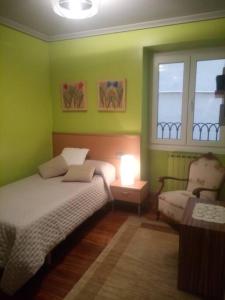 a bedroom with green walls and a bed and a chair at Céntrica, espaciosa y cómoda in Getaria