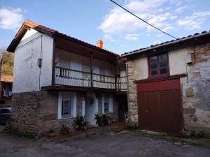 een oud stenen huis met een rode garage bij Casa Josefa in Villasuso de Cieza