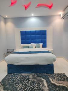 1 dormitorio con 1 cama grande y cabecero azul en جوهرة الاماكن, en Taymāʼ