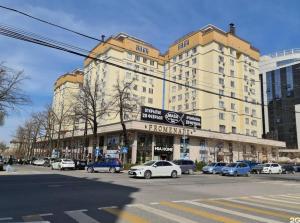 a large building with cars parked in a parking lot at Apartment in street Togolok Moldo 3 A in Bishkek