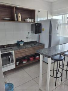 a kitchen with a counter and a table and a refrigerator at Lacqua diromaa com fogão, geladeira, micro-ondas, Park aquático 24h, acomoda até 5 pessoas in Caldas Novas