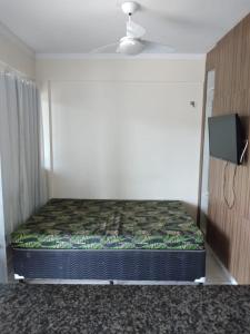 a small bed in a room with a television at Lacqua diromaa com fogão, geladeira, micro-ondas, Park aquático 24h, acomoda até 5 pessoas in Caldas Novas