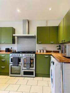 een keuken met groene kasten en een fornuis bij Modern and Comfy 5 Bed Home, Wi-FI, Free Parking! in Cambridge