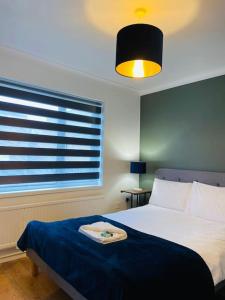 een slaapkamer met een bed met een blauwe deken en een raam bij Modern and Comfy 5 Bed Home, Wi-FI, Free Parking! in Cambridge