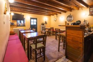 a dining room with tables and chairs and a bar at Troas Traditional Guesthouse in Vitsa