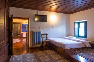 a bedroom with a bed and a tv on the wall at Troas Traditional Guesthouse in Vitsa