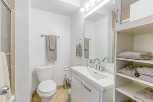 a white bathroom with a toilet and a sink at Downtown Apartments 12 in Toronto