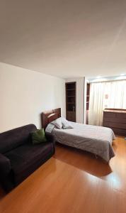 um quarto com uma cama e um sofá em Apto amplio en chico - calle 100 em Bogotá