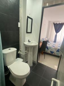 a bathroom with a toilet and a sink and a bed at Tunja Magic Habitación. in Tunja