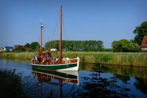 a boat is docked in the water on a river at Neu seit 2023 FeWo No 3 Friesenhuus Carolinensiel in Carolinensiel
