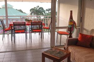 a living room with a table and chairs on a balcony at Appartement Coconut in Saint-François