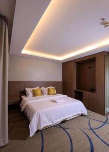 1 dormitorio con 1 cama blanca grande con almohadas amarillas en فندق سما السعوديه en Riad