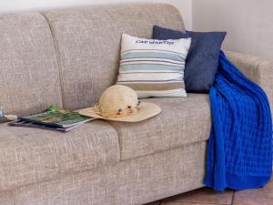 um chapéu de palha sentado num sofá com um livro em Apartment Mahalo by Interhome em Codaruina