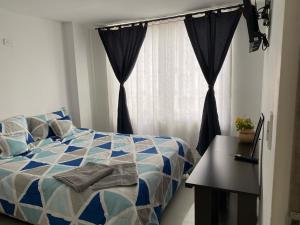a bedroom with a blue and white bed and a window at Tunja Magic Habitación in Tunja